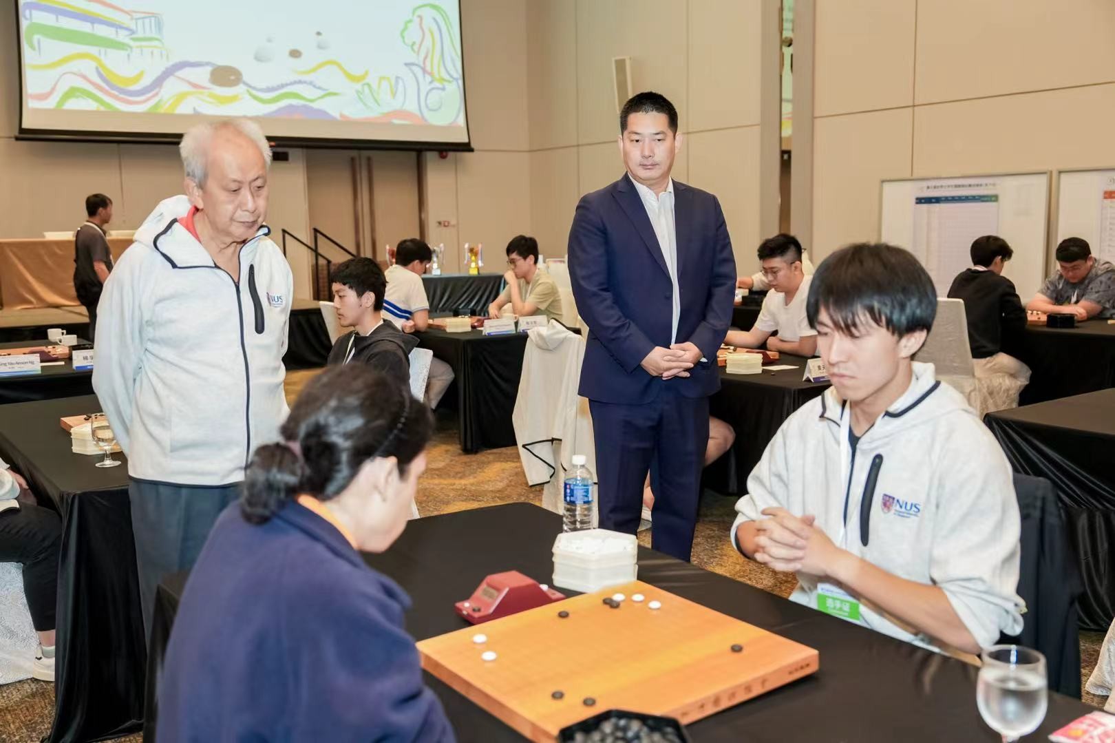 中国围棋协会主席常昊（右二）、新加坡围棋协会会(huì)长(zhǎng)陈(chén)丁(dīng)川(chuān)（左(zuǒ)一(yī)）观(guān)战(zhàn)。中(zhōng)国(guó)围(wéi)棋(qí)协(xié)会(huì)供(gōng)图(tú)